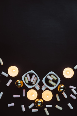 Winter composition. Two cups of coffee with marshmallows and candles on a dark background.の写真素材