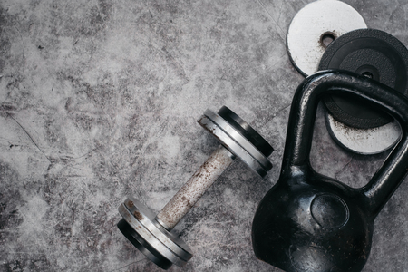 Fitness or bodybuilding concept background. Old iron dumbbells and Kettlebell on grey, conrete floor in the gym. Top view. Healthz lifestyle.の写真素材