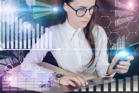 Woman in glasses working on a project in loft office. Woman develops marketing plan. Laptop and...