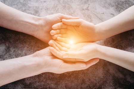 Light in young family hands offering help, protection and support symbol. Sharing hope conceptの写真素材
