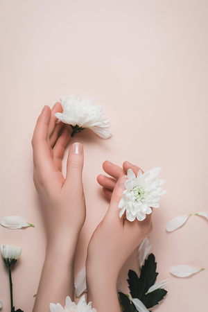 Top view beautiful female hands with white flowers on pastel pink background. Care about nails and clean, soft, smooth skin. Manicure, pedicure beauty salon. Flat lay, top view, copy space.の写真素材