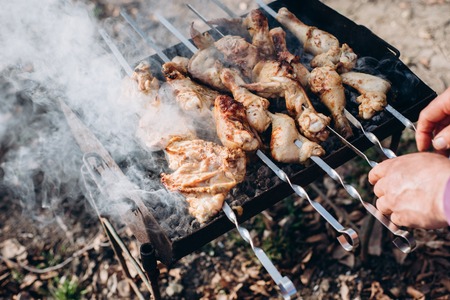 Closeup photo of barbecue grill with chicken meat on outdoor in the summer time. Man cooking food in nature. Concept adventure active vacations outdoorの写真素材
