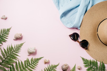 Feminine summer fashion composition with blouse, hat, sunglasses, fern, seashell on pink background....