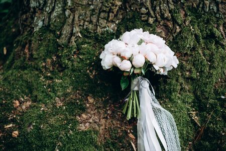 Close-up image of a beautiful and stylish wedding bouquet of white and pink peonies on wooden background.の写真素材