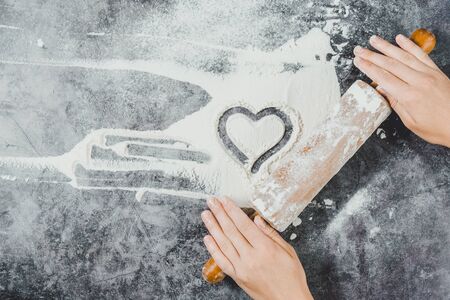Baking background. Heart of flour, rolling pin and female hands on gray table. Bake menu, recipe, homemade pastry concept. Top view. Banner with copy space for your text. Valentine's Dayの写真素材