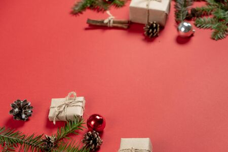 Christmas or winter composition. Handmade gift boxes decorated with craft paper of fir tree branches, pine and cinnamon on pastel red background. Flat lay, top view, copy spaceの写真素材