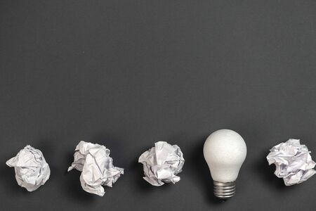 New idea concept with crumpled office paper and white light bulb on black background. creative...