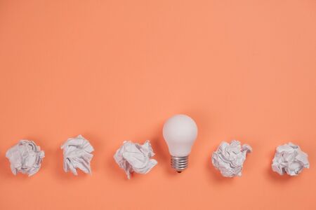 Creativity inspiration, great business idea concept with white light bulb and paper crumpled ball on...
