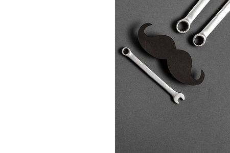 Fathers Day mockup with retro stylish black funny paper moustache and combination wrenches on grey...