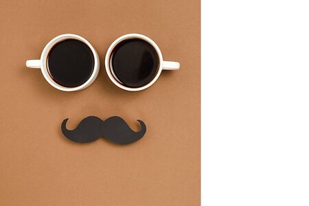 Two cup coffee, stylish black paper photo booth props moustaches on brown and white background. Copy space for inscriptions. Holiday Concept.の写真素材