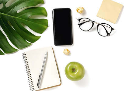 Top view office table desk. Workspace with pen, monstera leaves, eyeglasses, notebook, apple, modern...