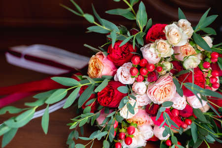 Close-up image of a beautiful and stylish wedding bouquet of red, pink roses and eucalyptus...