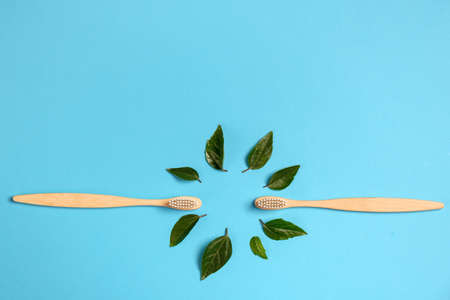 Zero waste. Two wooden bamboo eco friendly toothbrushes and green leaf on blue background. Dental care and Eco friendly and reuse concept. Flat lay, top view, copy spaceの写真素材
