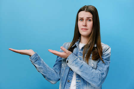 Young displeased woman looking camera pointing showing fingers hands on workspace copy space mock up...