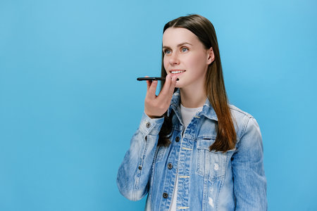 Millennial female holding phone speak activate virtual digital voice assistant on smartphone, girl...