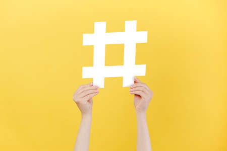 Cropped images of female hands holding large big white hashtag sign, viral web content, internet...