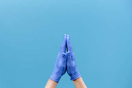 Close up of unrecognizable male in medical protective gloves holds hands in prayer to god,...