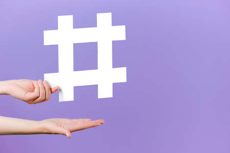 Concept of trendy social media posts and blogging. Female hands holding large big white hashtag...