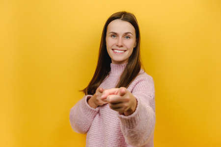 Portrait of happy attractive smiling friendly young woman 20s wearing pink knitted sweater point...