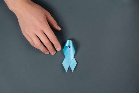Symbol for support men. Male hand and blue ribbon on gray background. Prostate Cancer Awareness,...