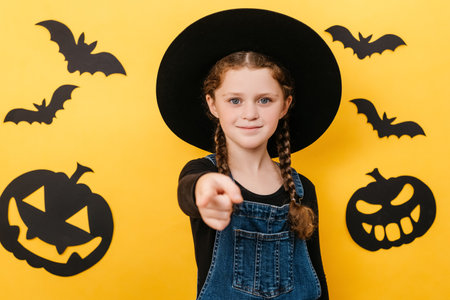 Portrait of adorable little girl kid wears black hat, point index finger camera on you motivation...