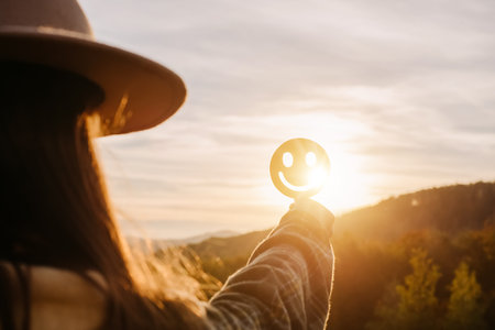 Side view of young female holding happy smile face on background amazing sunset in mountains at autumn calm day, good feedback rating and positive customer review, satisfaction survey, mental healthの写真素材