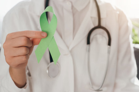 Close up of woman doctor in white coat with stethoscope holding lime green ribbon sitting on couch, Mental health awareness, world mental health day, world kidney day, organ donation conceptの写真素材