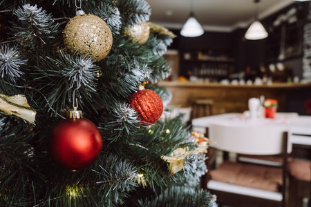 Close-up of Christmas tree with lights garland in modern coffee room with served table, festive decorated empty apartment cafe for New Year celebration, winter holiday concept. selective focusの写真素材
