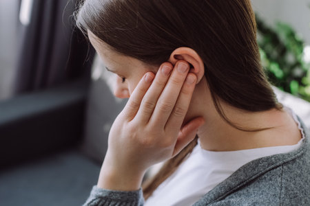 Tinnitus concept. Close up up of sick young caucasian female touch plug ear suffer from noisy...