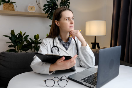 Pensive woman doctor sit at table holding clipboard with smile plan future work relax dream. Calm female medic rest look at distance feel glad helping patients. Concept modern technology in medicineの写真素材