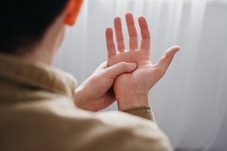 Close up back view of young man with shaking of Parkinson's disease, symptom of resting tremor, male holding hand to control hands tremor, neurological disorders, brain problems, health care conceptの写真素材