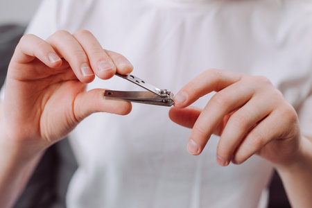 Female hands manicure with nail clipper cutting fingernail on long or dirty finger, using nail sharp clipper make with stainless steel. Hygiene concept. Healthy care clean body by cut short trimの写真素材