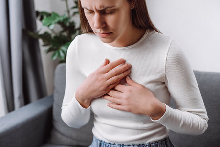 Acid reflux disease. Young woman sitting on sofa have symptom gastroesophageal, esophageal, stomach...