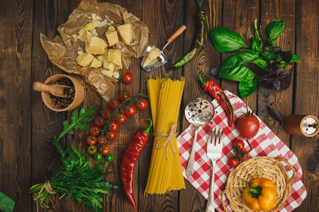 Pasta background. Dry spaghetti with vegetables and herbs on a wooden table.Free text spaceの写真素材