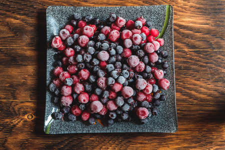 frozen black and red currants on a wooden tableの写真素材
