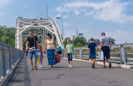 Dnepropetrovsk, Ukraine - August 15, 2015: Group of people walking through pedestrian bridge from central park to Komsomolsky island on a Dnepr riverのeditorial素材