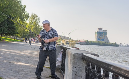 Dnepr, Ukraine - August 21, 2016: Senior fisherman casting the line while fishing on a Dnepr river embankment at summer weekendのeditorial素材