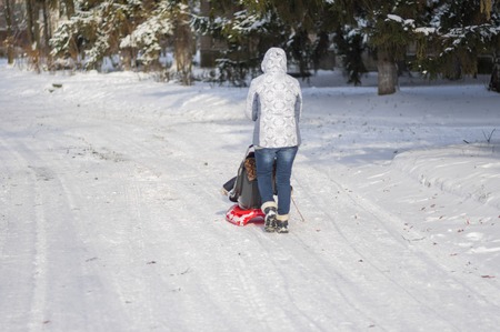 DNEPR, UKRAINE - DECEMBER 04, 2016:Mother walking on an empty, snowy street driving modern sledge with kid in Dnepr, Ukraine at December, 04 2016のeditorial素材