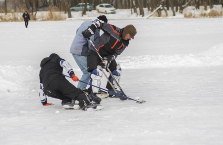 Dnipro, Ukraine - January 27, 2018: Three mature amateur men fighting for the puck while playing hockey on a frozen river Dnepr in Ukraineのeditorial素材