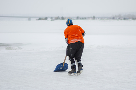Dnipro, Ukraine - January 28, 2018: Amateur hockey player cleaning playground with shovel between game periods on a frozen river Dnipro in Ukraineのeditorial素材