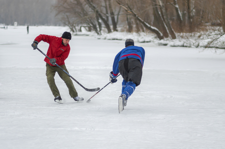 Dnipro, Ukraine - January 28, 2018: Two mature men fighting for the puck while playing hokey on a frozen river Dnipro in Ukraineのeditorial素材