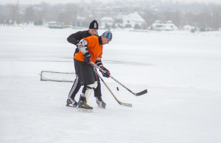 Dnipro, Ukraine - January 28, 2018: Young man fighting with mature man for the pack  while playing hockey on a frozen river Dnipro in Ukraineのeditorial素材