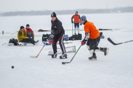 Dnipro, Ukraine - January 28, 2018: Group of different aged people playing hokey and resting on an iced river Dnipro in Ukraineのeditorial素材