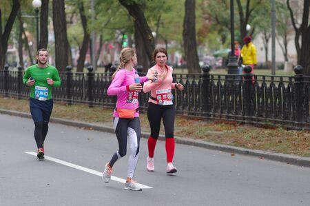 DNIPRO, UKRAINE - SEPTEMBER 22, 2019: Female participants exchanging with drink bottles while running on Dnipro city street during 42 km distance of ATB Dnipro Marathonのeditorial素材