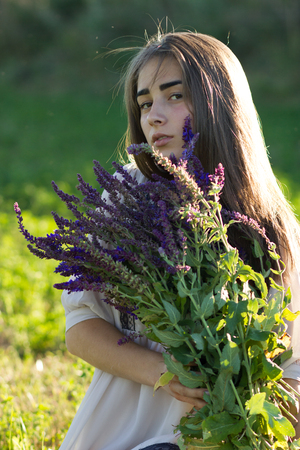 Beautiful girl iwith lavender bouquet and retro dress in the field. Girl collect lavender. Soft focusの写真素材