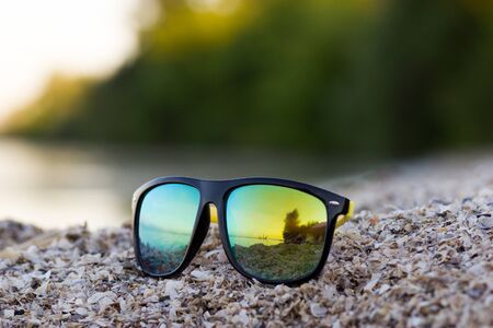 Color sun glasses lie on a beach near the sea shoreの写真素材