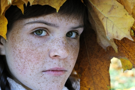 close-up portrait of freckled teenage girl in the autumn parkの写真素材