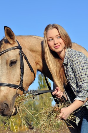 teenage girl feeding horse in sunny dayの写真素材
