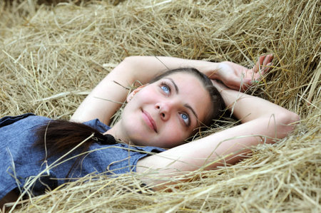 young attractive woman relaxing on the haystack in summer dayの写真素材