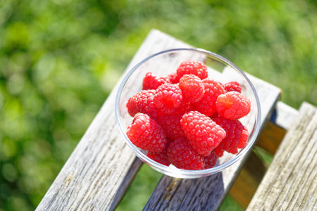 Ripe raspberries in a glass bowl on a wooden table. selective focus. Low DOF